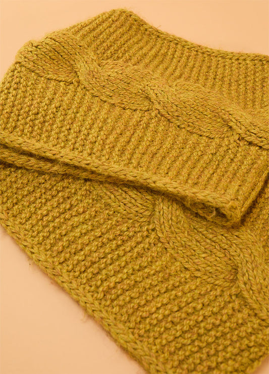 Close-up of the Honey Cable Cowl, a hand-knitted mustard yellow cowl featuring a wide braided cable pattern against a textured stitch background.