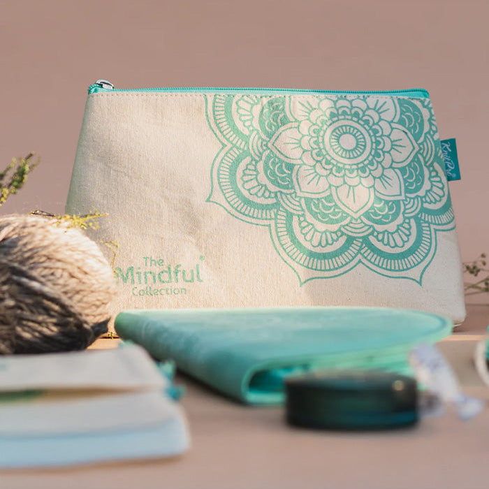 Green and white purse with a floral design, featuring a mandala charm and zippered pocket for knitting supplies.