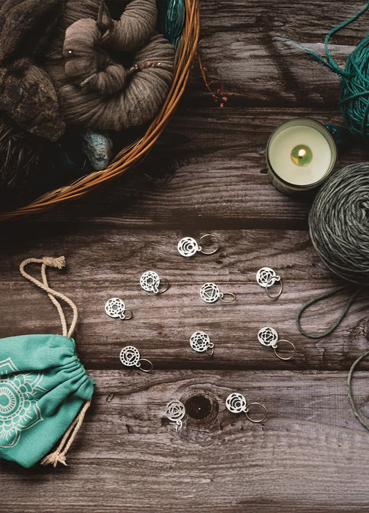 A basket filled with colorful yarn, a lit candle, and a bag of yarn, showcasing a cosy crafting atmosphere.