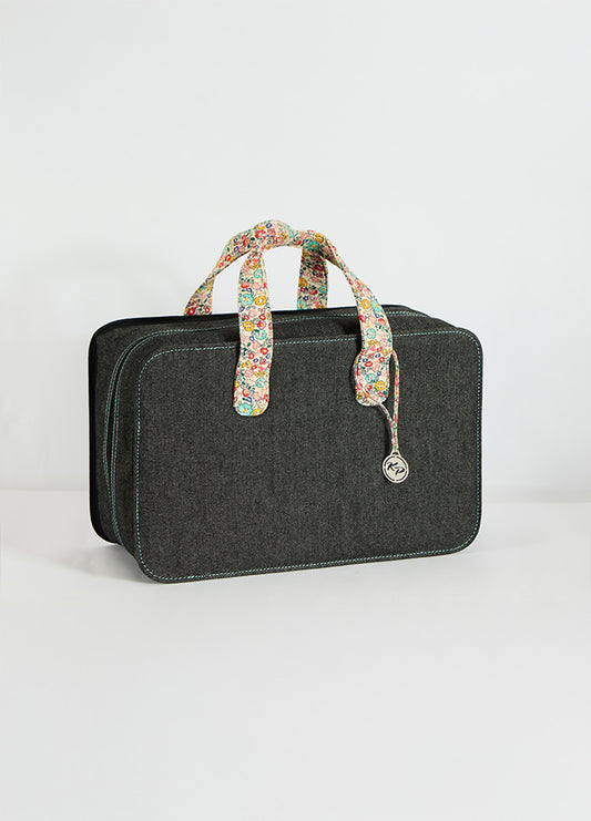 Large black suitcase with floral print handles, ideal for yarn and project storage, equipped with zippered pockets and interior dividers.