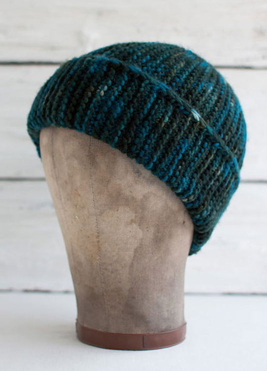 Paper Bag Cap on mannequin head, hand-knit in ribbed texture with alternating dark green and blue stripes.