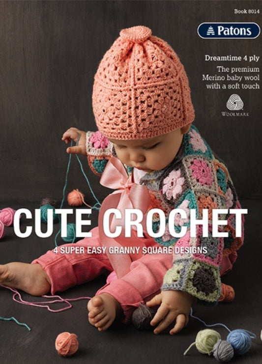 A baby in a pink crocheted hat and colorful granny square sweater sits on a dark surface, surrounded by yarn balls. Text: "Cute Crochet." Cozy, playful vibe.
