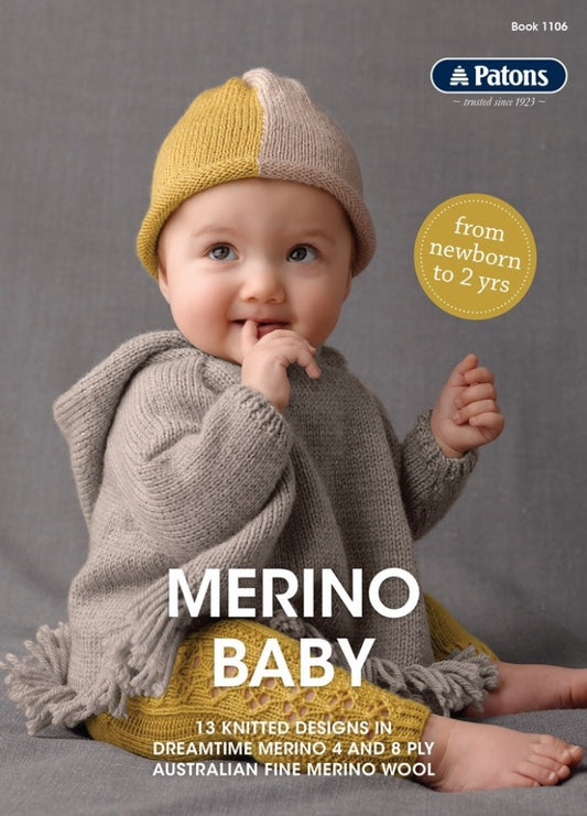 Baby wearing a knitted outfit with a gray poncho and a yellow-beige hat sits on a gray surface, smiling with fingers in mouth. Text reads "MERINO BABY."