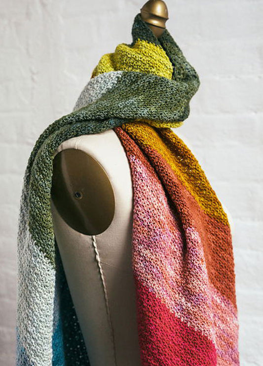 Rainbow Showers Scarf draped on mannequin, hand-knit with a gradient of green, yellow, pink, red, and orange.