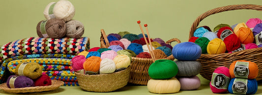 Colourful assortment of knitting yarn balls, crochet projects and craft supplies arranged in baskets.