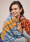 A woman models a stylish knitted scarf, highlighting its intricate design and vibrant color.