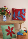 Two decorative pillows featuring vibrant patterns and colorful yarn accents arranged on a soft surface.