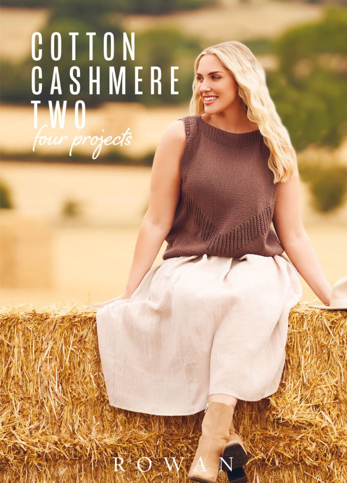 Woman with long blonde hair smiles while sitting on a hay bale, wearing a brown knit top and white skirt. Background shows a blurry pastoral setting.