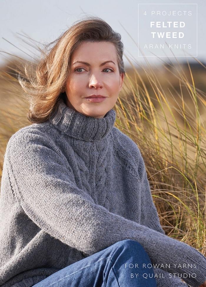Woman in a gray knitted turtleneck sweater sits in tall grass, gazing thoughtfully to the side. The scene is serene, with an overcast sky. Text on the image reads, "4 Projects Felted Tweed Aran Knits."