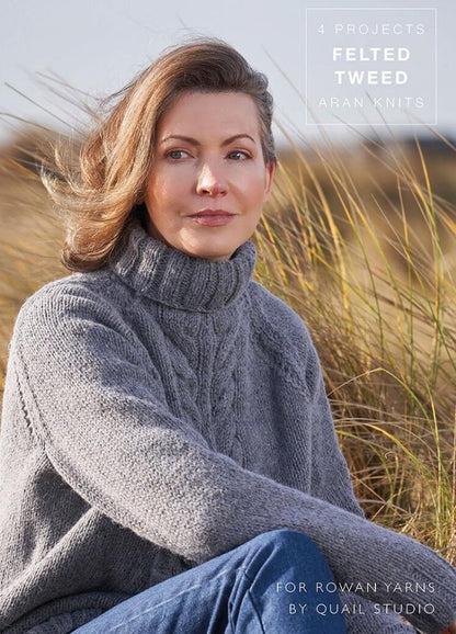 Woman in a gray knitted turtleneck sweater sits in tall grass, gazing thoughtfully to the side. The scene is serene, with an overcast sky. Text on the image reads, "4 Projects Felted Tweed Aran Knits."