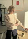 Oversized beige Balloon Sweater with soft balloon sleeves and tapered cuffs, worn casually with denim.