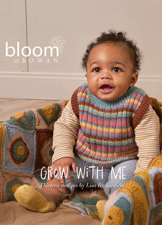 A smiling baby sits in a knitted multicolored vest, surrounded by a cozy textured blanket. The scene conveys warmth and comfort. Text reads "Bloom at Rowan" and "Grow With Me" by Lisa Richardson.