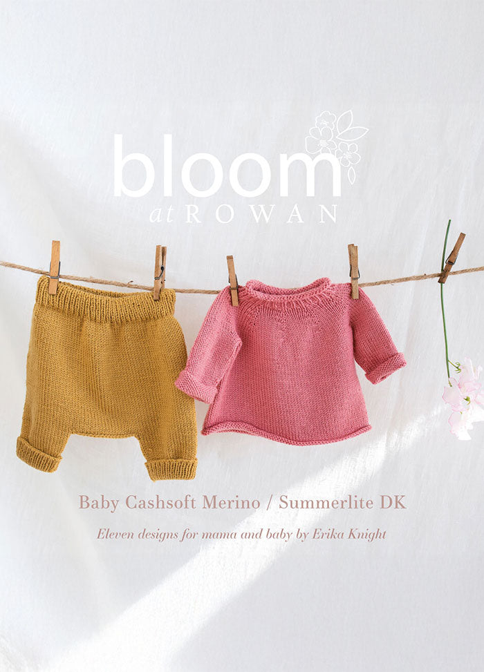 A photo of miniature knitted children's clothing hanging on a line—mustard pants and a pink sweater. The background is white, with floral accents and text reading 'bloom at ROWAN.' The tone is soft and cozy.