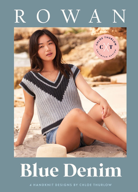 A woman in a striped knit top and denim shorts sits on a sandy beach, exuding a relaxed vibe. Text overlay: "Rowan Blue Denim" by Chloe Thurlow.