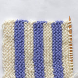 A close-up image of a knitting stitch with a purple and white striped pattern, in the colour Jacaranda