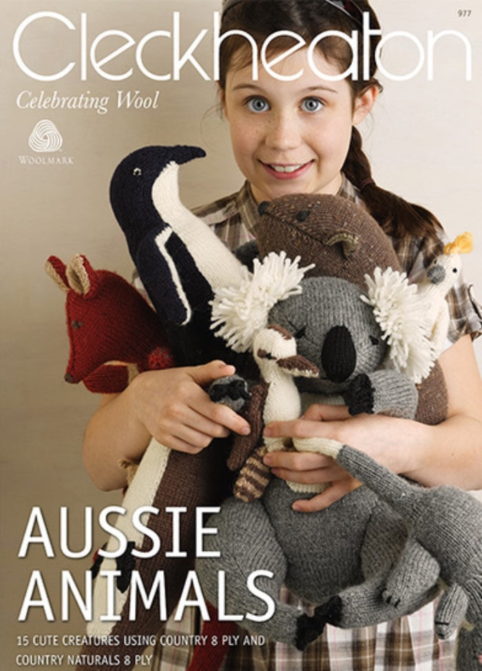 Young girl smiling, holding knitted Australian animals like a koala and kangaroo. Text above reads “Cleckheaton” and below “Aussie Animals.” Warm, cheerful tone.