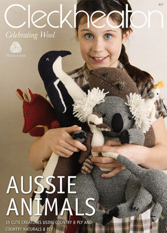 Young girl smiling, holding knitted Australian animals like a koala and kangaroo. Text above reads “Cleckheaton” and below “Aussie Animals.” Warm, cheerful tone.