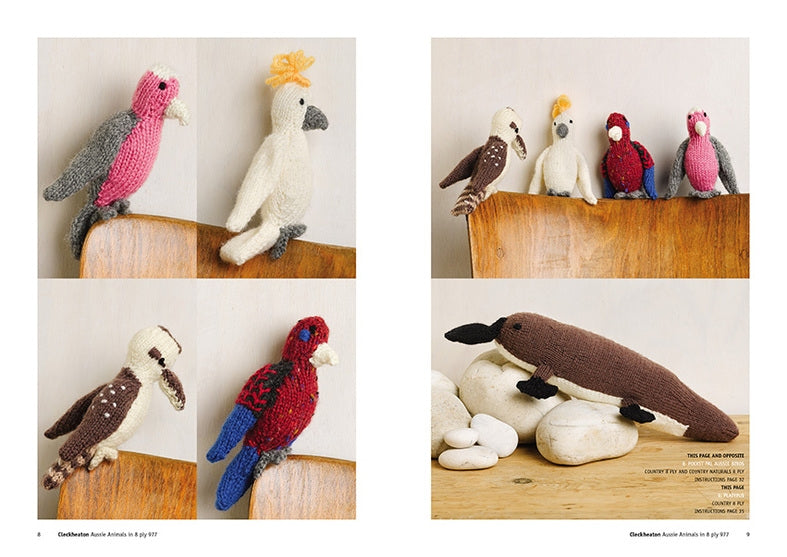 Knitted birds perch on a wooden chair, showcasing vibrant colors like pink, red, and blue. A knitted platypus rests on white stones nearby. Cozy and whimsical.