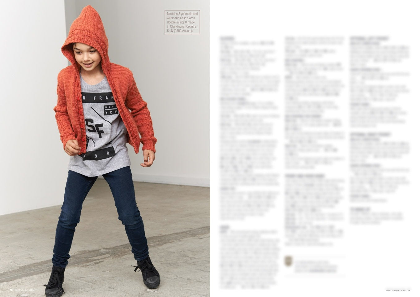 A child wearing a red hooded cardigan, gray graphic tee, and jeans playfully poses indoors, looking happy and energetic on a concrete floor.