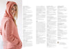 A woman in a pink knitted hoodie with intricate cable patterns smiles while looking at the camera. The right side shows blurred text, suggesting a magazine layout.