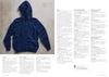 Blue hooded cardigan with front pockets and button closure, laid flat on a textured surface. Adjacent text columns are blurred, keeping focus on the sweater.
