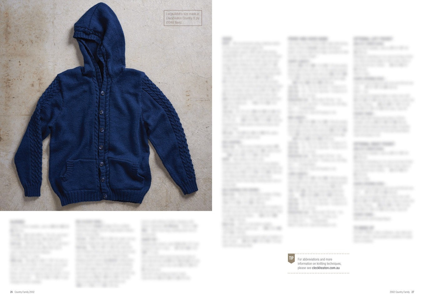 Blue hooded cardigan with front pockets and button closure, laid flat on a textured surface. Adjacent text columns are blurred, keeping focus on the sweater.