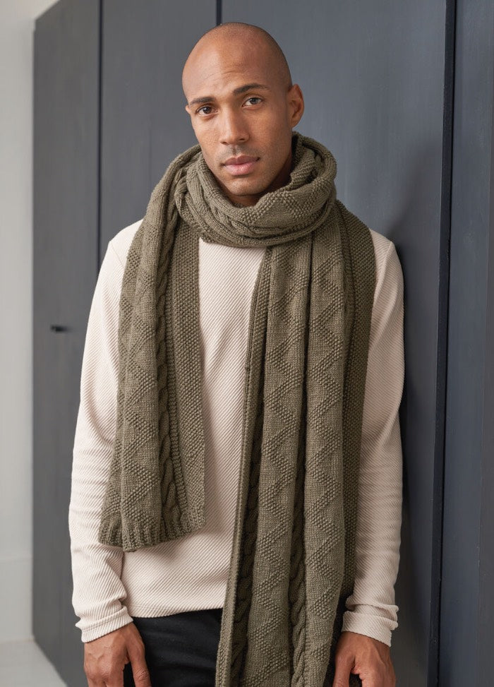 A man wearing an olive green knitted scarf, showcasing a textured pattern and a cozy, warm appearance.