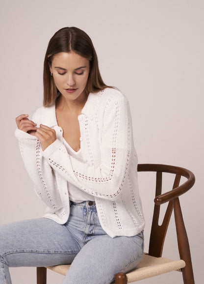 Model in a cropped cotton sweater with wide sleeves and ribbed hem.