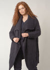 A fitted, round-neck pullover in solid navy blue with fine ribbing at the cuffs and hem, worn casually over trousers.