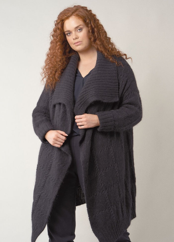 A fitted, round-neck pullover in solid navy blue with fine ribbing at the cuffs and hem, worn casually over trousers.