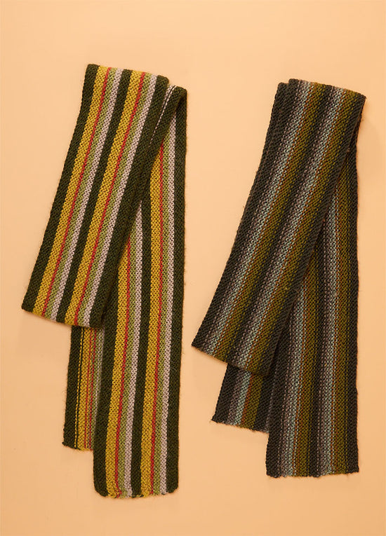 Two hand-knitted striped scarves hanging side by side against a beige background – left scarf features green, yellow, pink, and white stripes; right scarf includes dark green, gray, yellow, and blue stripes, showcasing colourful variations of the Crown Street design.