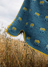 Achillea Scarf': Blue scarf with yellow Achillea floral pattern and border, displayed over tall grass outdoors.