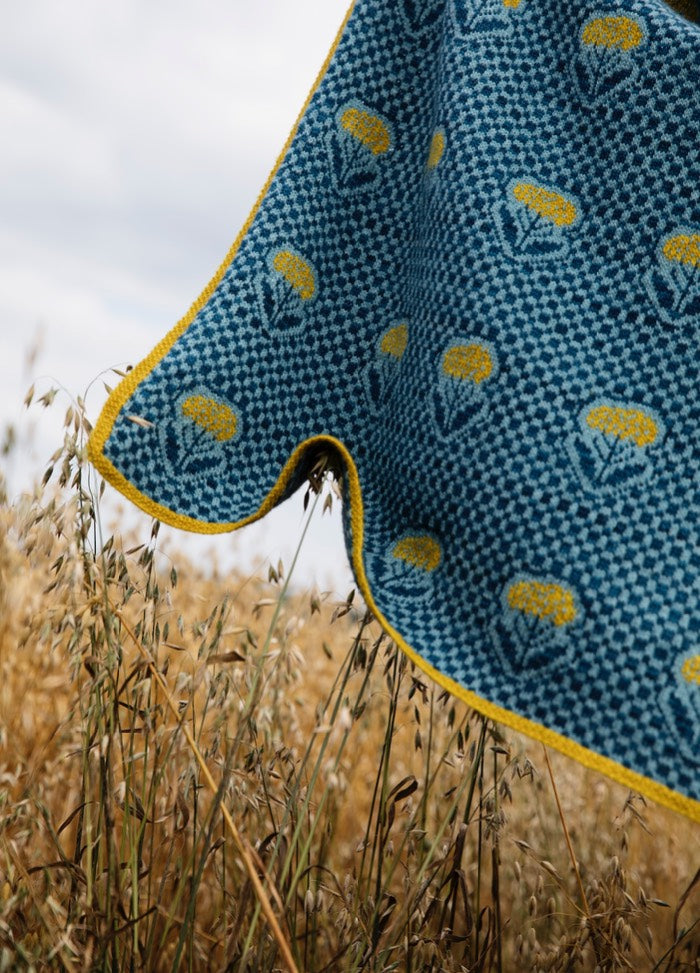 Achillea Scarf': Blue scarf with yellow Achillea floral pattern and border, displayed over tall grass outdoors.