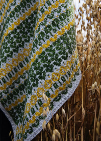Dreaming in the Park Scarf': Light gray scarf with green and yellow diamond and floral motifs, draped over dry grass.