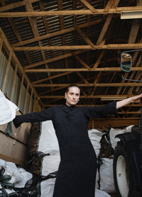 Frankie Dress': Black dress worn inside a wooden structure with high beams, surrounded by large white bags and a vehicle.