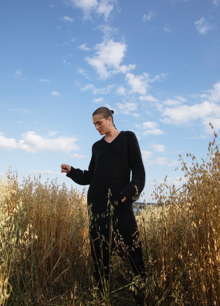 January Dress': Black long-sleeve top and pants worn in a field of tall grass under a partly cloudy sky.