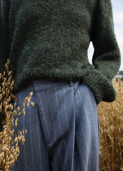 Liberty Sweater': Green textured sweater paired with blue pinstriped pants, worn in a field of tall dry grass.