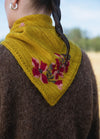 Wallflower Scarf': Mustard yellow triangular scarf with red, pink, and green floral pattern, draped over shoulders.