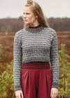 Person wearing the Dales Sweater, a textured grey knit with long sleeves, paired with maroon pants in an open field setting.