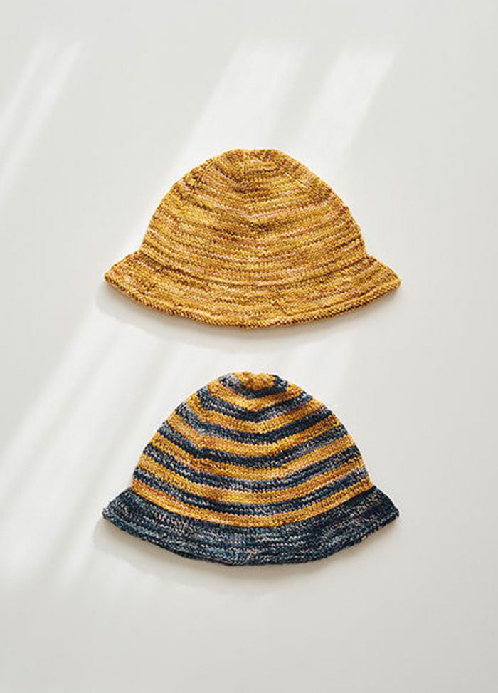 Two Delmira Hats: one solid yellow, one striped yellow and dark blue, displayed together.