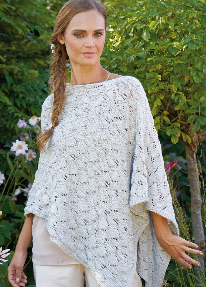 Delphine Poncho knitting pattern, a flowing lace poncho with botanical-inspired stitchwork, styled for outdoor wear.