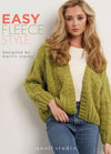 A woman in a light green knitted cardigan and jeans poses confidently against a white wall. Text above reads, "Easy Fleece Style, designed by Martin Storey." The mood is cozy and stylish.