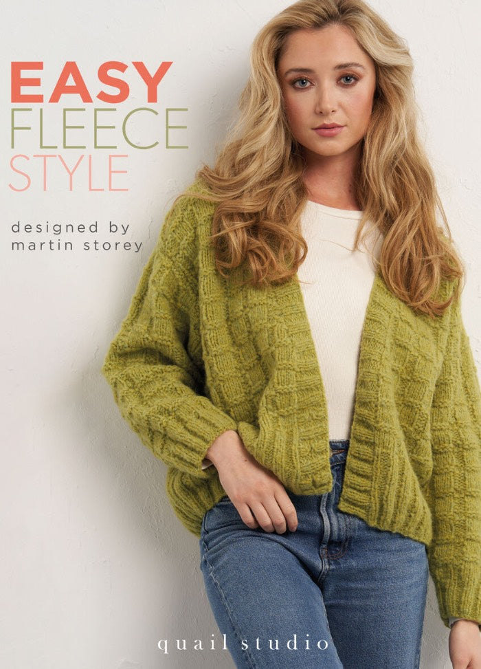 A woman in a light green knitted cardigan and jeans poses confidently against a white wall. Text above reads, "Easy Fleece Style, designed by Martin Storey." The mood is cozy and stylish.