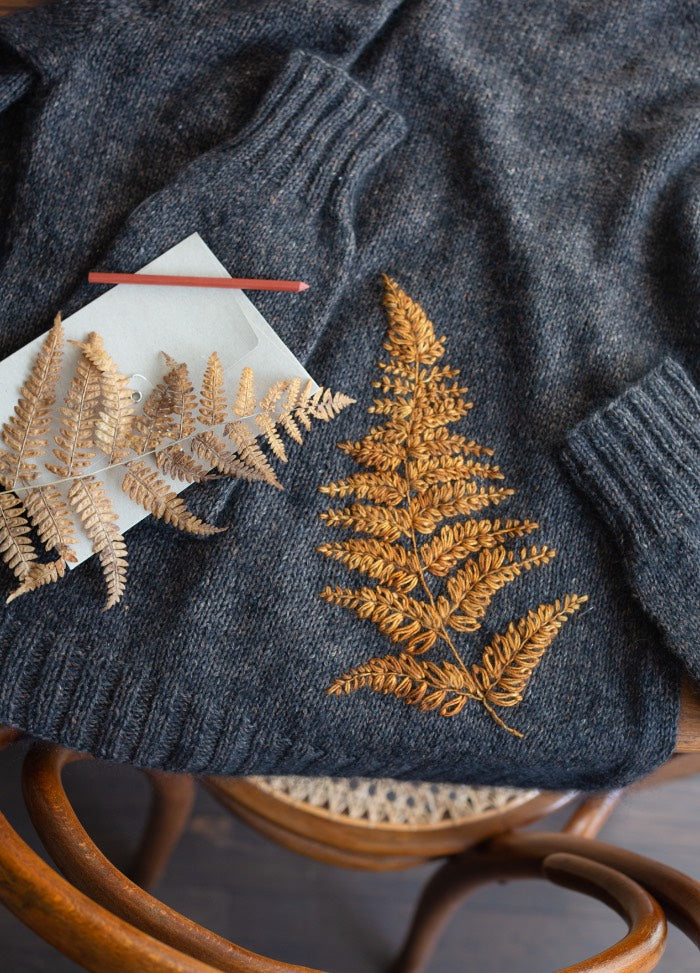 Fireworks: floral burst embroidery on shoulder of gray knit cardigan, resembling firework blooms.