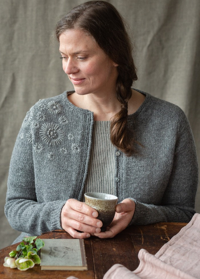 Flieder: embroidered branches with pink, orange flowers and yellow seed clusters on dark knit sweater.