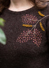 Floral Crest: pink, blue, and orange floral embroidery arranged in a crest shape on knit sweater.