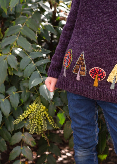 Trees: multicolored tree motifs embroidered near hem of dark purple knit sweater.