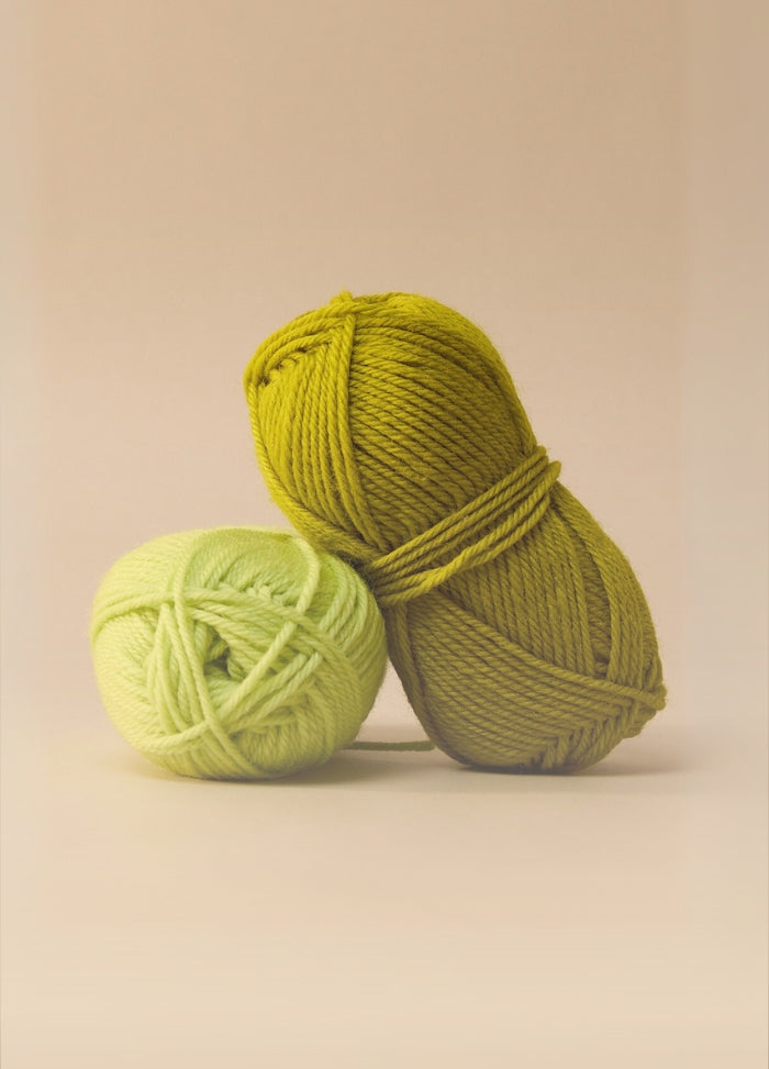Two colourful balls of machine washable wool yarn displayed on a beige background, highlighting their 10ply weight and care instructions.