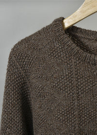 Close-up of the Esther Sweater in brown textured knit with diamond pattern and ribbed neckline, displayed on a wooden hanger.