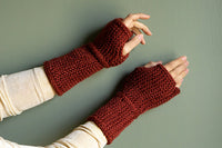 Everyday Handwarmers, hand-knit in deep red yarn, fingerless style, shown on hands.
